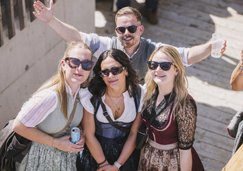 Drei Frauen und ein Mann in Tracht lächeln in die Kamera.