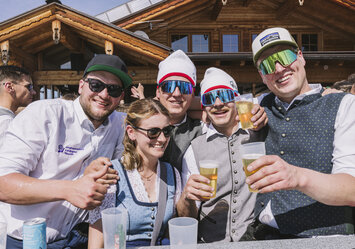 Vier Männer und eine Frau in Tracht trinken Bier.