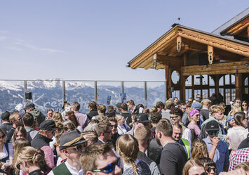 Eine Menschengruppe in Tracht feiert zusammen im Freien.