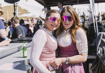Zwei Frauen in Tracht und mit Sonnenbrille posieren für ein Foto.