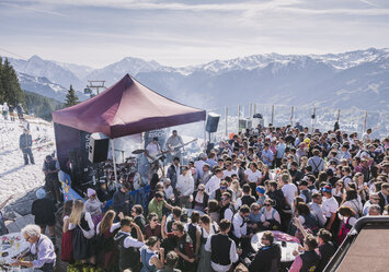 Eine große Menschengruppe in Trachtenkleidung feiert zusammen im Freien.