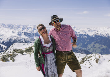 Ein Mann und eine Frau posieren vor einer verschneiten Bergkulisse.