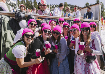Eine Gruppe Frauen in Tracht trägt alle eine pinke Mütze.