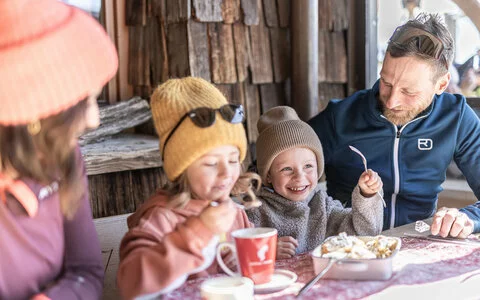 Eine Familie genießt Kakao und Kaiserscharren auf einer Hütte