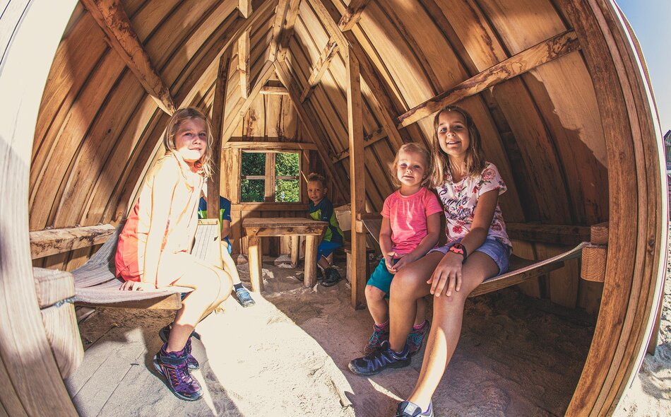 Kinder sitzen in einer Hütte im Sandkasten