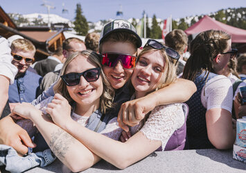 Ein Mann umarmt zwei Frauen.
