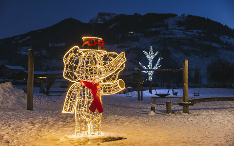 Weihnachtlich beleuchteter gelber Elefant mit Hut im Schnee