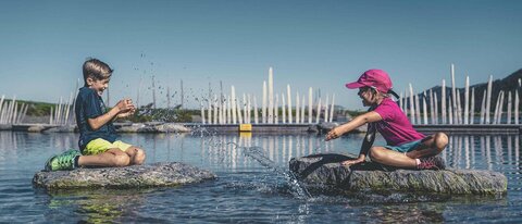 Ein Mädchen und ein Junge spielen im Wasser.