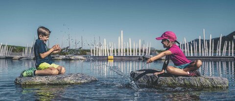 Ein Mädchen und ein Junge spielen im Wasser.
