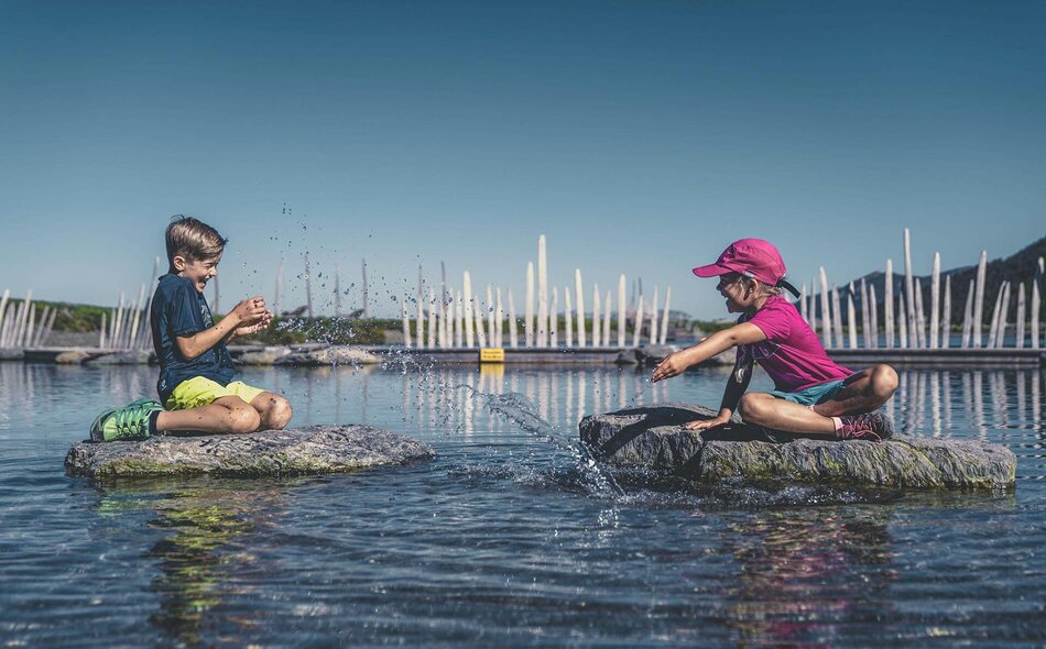 Ein Mädchen und ein Junge spielen im Wasser.