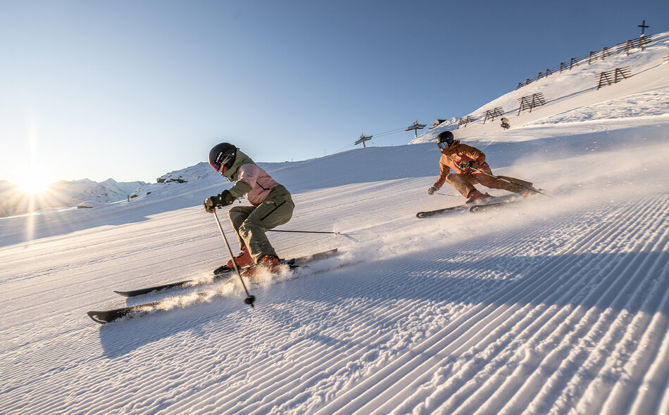 Zwei Skifahrer fahren eine Piste hinunter