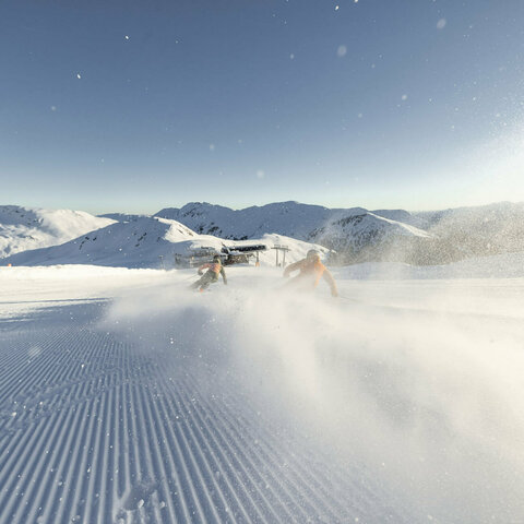 Zwei Skifahrer rasen die Piste hinunter