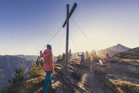 Ein Mann und eine Frau stehen am Gipfelkreuz
