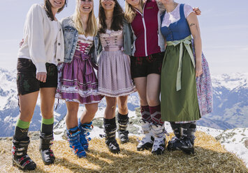 Fünf Frauen in Tracht stehen zusammen auf einem großen Heuballen.