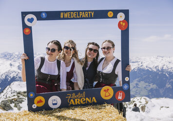 Vier Frauen in Trachtenkleidung posieren mit einem Bilderrahmen.
