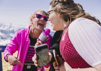 Zwei Frauen singen in ein pinkes Mikrofon.