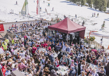 Eine große Menschengruppe feiert zusammen neben der schneebedeckten Piste.