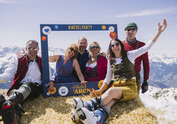 Sechs Personen in Tracht posieren für ein Foto auf einem Heuballen.