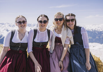 Vier Frauen in Dirndl und Sonnenbrille posieren für ein Foto.