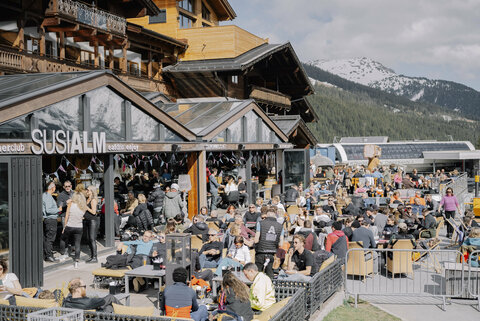 Menschen auf einer Sonnenterrasse im Hintergrund die Königsleiten Bergbahn