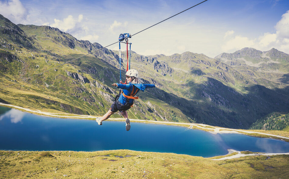 Eine Frau fährt mit einer Zipline über der traumhaften Natur