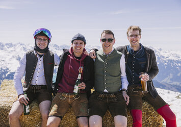 Vier Männer sitzen auf einem Heuballen.