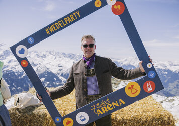 Ein Mann in Tracht posiert mit einem Bilderrahmen.
