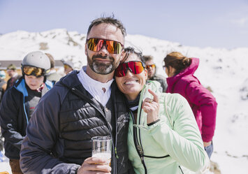 Ein Mann und eine Frau mit Sonnenbrille lachen in die Kamera.