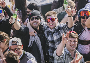 Zwei Männer in Sonnenbrillen posieren für ein Foto mit Bier in der Hand.