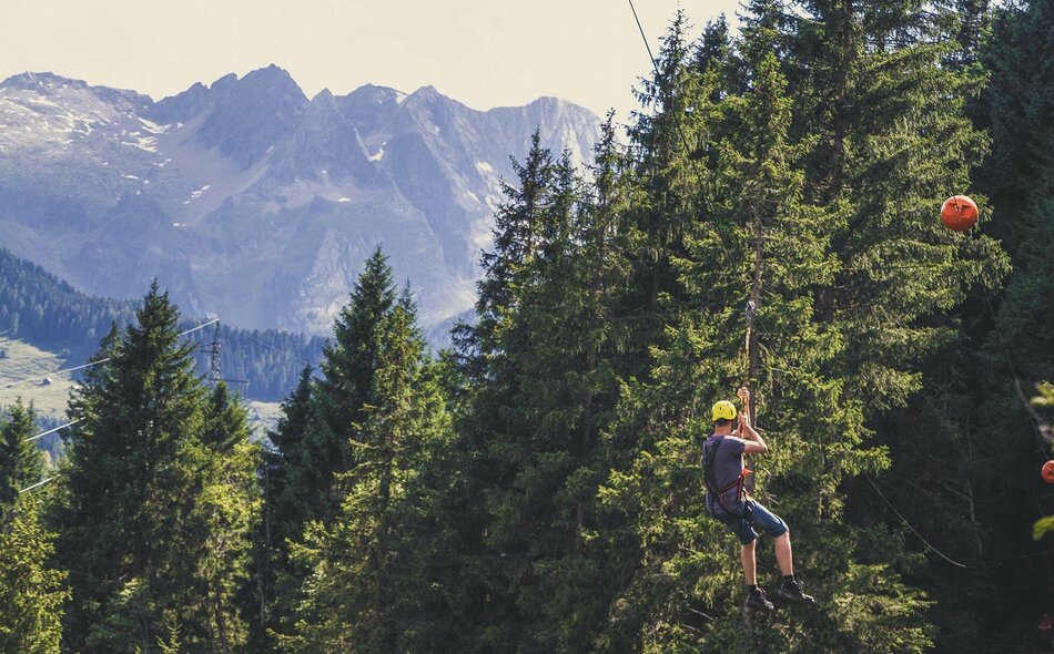 Eine Mann fährt mit einer Seilrutsche durch den Wald