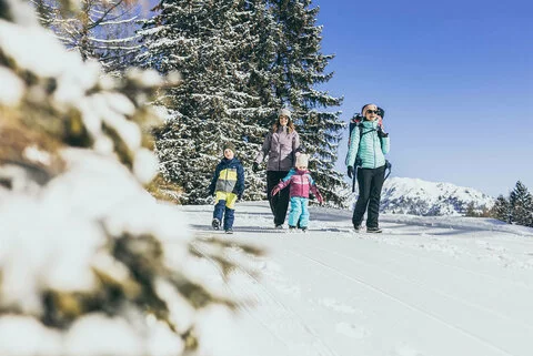 Zwei Frauen und drei Kinder spazieren durch den Schnee