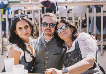 Ein Mann und zwei Frauen in Tracht posieren für ein Foto.