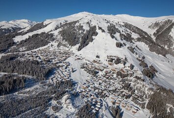 Blick auf ein schneebedecktes Dorf mit verschneiten Häusern und winterlichen Landschaften