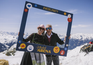 Ein Mann und eine Frau posieren im Schnee mit einem Bilderrahmen.