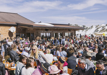 Eine große Menschengruppe sitzt zusammen im Freien.